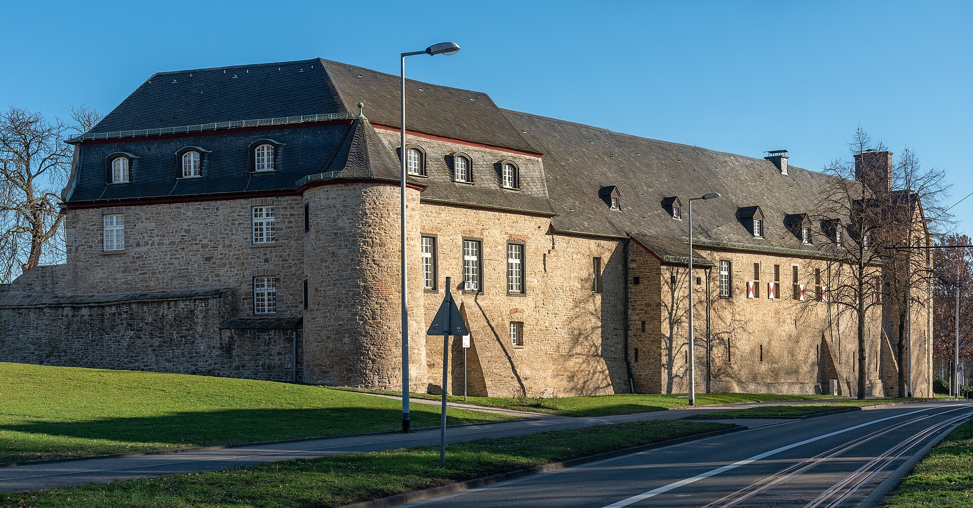 Straßenseite von Schloss Broich in Mülheim mit alter Mauer und Eingang